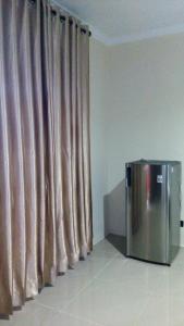 a stainless steel refrigerator sitting in front of a curtain at Rasti Homestay in Kuta Lombok