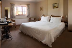 a bedroom with a large white bed and a desk at Larkrise Cottage Bed And Breakfast in Stratford-upon-Avon