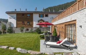 a patio with chairs and an umbrella in front of a building at Hotelino Petit Chalet in Celerina