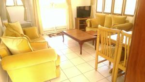 ein Wohnzimmer mit gelben Stühlen und einem Tisch in der Unterkunft Corinya Serviced Apartments in Entebbe
