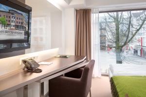 a hotel room with a desk with a phone and a television at Bergmann Boardinghouse Osnabrück in Osnabrück