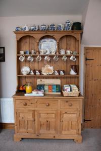 a wooden cabinet with plates and bowls on it at Larkrise Cottage Bed And Breakfast in Stratford-upon-Avon +9 photos