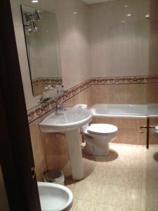 y baño con lavabo, aseo y bañera. en Hostal Torres, en San Leonardo de Yagüe
