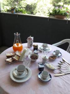 Biały stół z talerzami i kubkami oraz wazon w obiekcie Bed and Breakfast Silvana w mieście Tarent