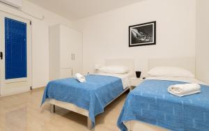 two beds in a white room with blue sheets at Villa Doris in Neum