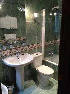 łazienka z toaletą, umywalką i wanną w obiekcie Hostal Torres w mieście San Leonardo de Yagüe
