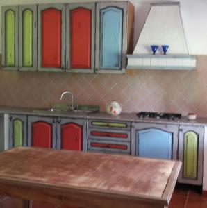 a kitchen with colorful glass cabinets and a wooden table at Casa Marina Lu Tuvaraggiu Casa vacanze in Sorso +32 photos