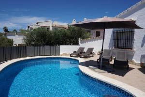 una piscina con sombrilla y sillas en Muriel House, en Monte Pego