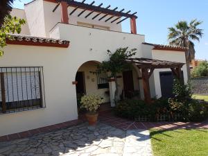 Biały dom z łukowym wejściem w obiekcie Casa Chalet Las Camelias w mieście Los Barrios