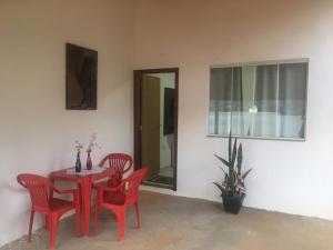 - une table et des chaises rouges dans une chambre avec fenêtre dans l'établissement Suite independente em casa de fazenda, à Capitólio