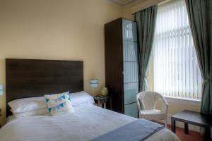 a bedroom with a bed and a chair and a window at Kildonan Guest House in Aberdeen
