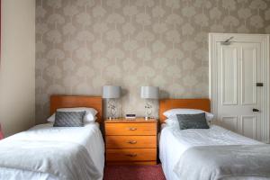 a bedroom with two beds and a dresser with two lamps at Kildonan Guest House in Aberdeen