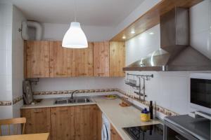 una cocina con armarios de madera y fregadero en Apartamento Torcal Écija, en Écija