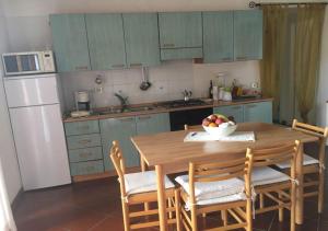 a kitchen with a wooden table with chairs and a bowl of fruit at Casa Asparagi in San Teodoro