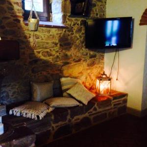 a living room with a couch and a tv on a stone wall at Casa di Meo in Buti