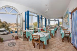 a restaurant with tables and chairs and windows at Hotel Giglio in Lampedusa