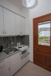 uma cozinha com armários brancos, um lavatório e uma janela em Villa Zacharo em Skala