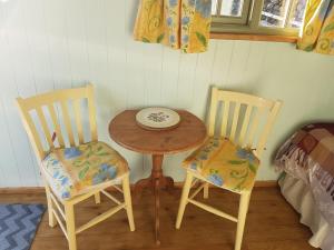 two chairs and a small table with a plate on it at Shepherds hut Dolly wagon in Keswick