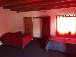 1 dormitorio rojo con 2 camas y ventana en Apart Tierra Sureña en Catriel