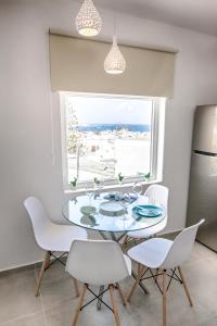 ein Esszimmer mit einem Tisch, Stühlen und einem Fenster in der Unterkunft Sole Mare Villa in Mykonos Stadt