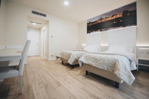 a white bedroom with two beds and a desk at Cascina Speranza Hotel in Riva presso Chieri