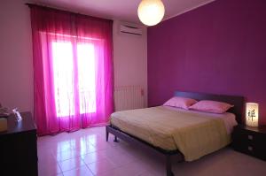 a bedroom with pink walls and a bed with pink pillows at Appartamento con Vista a Venturina in Venturina Terme