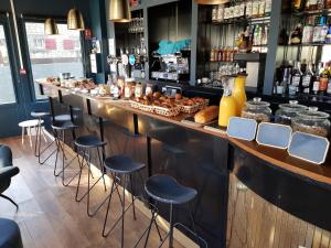 - un bar avec tabourets et un comptoir avec nourriture dans l'établissement Hotel Des Arts, à Wimereux