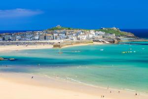 a group of people on a beach near the water at Trevose Harbour House in St Ives