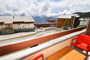 a red chair on a balcony with a view of mountains at Le Lauranoure - 205 in L'Alpe-d'Huez