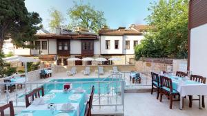 um restaurante com mesas e cadeiras ao lado de uma piscina em Urcu Hotel em Antalya