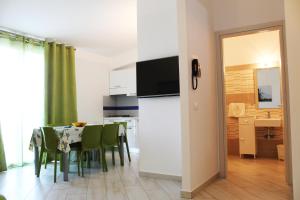 a kitchen and dining room with a table with green chairs at Borgo Aranci - Villetta Peonia B3 - Castellammare del Golfo in Castellammare del Golfo