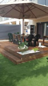 a wooden deck with a table and chairs and an umbrella at Résidence Golf Panoramica in Sant Jordi