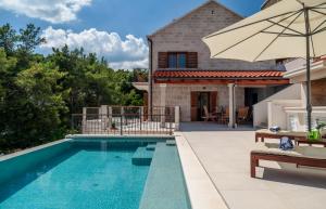 a swimming pool with an umbrella and a house at Villa Nova Brac in Sumartin