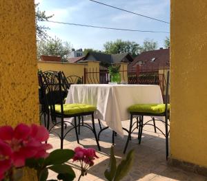 a table and chairs with a white tablecloth on a patio at Kiskut Liget Pension in Győr