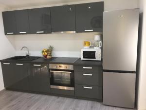 a kitchen with black cabinets and a white refrigerator at Sunflower in Kaštela