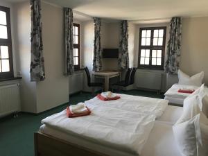 a room with two beds and a desk and windows at Schlossgasthaus Lichtenwalde in Lichtenwalde