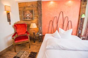 a bedroom with a bed and a red chair at Ringhotel Alpenhof - Patchworkhotel in Augsburg