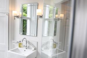 a bathroom with two sinks and a shower and mirrors at Latimer House in Bowness-on-Windermere