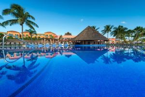 a large swimming pool with palm trees and a resort at Ocean Coral & Turquesa All Inclusive in Puerto Morelos