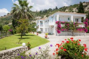 a large white house with flowers in the yard at Vivian Apartments in Vlachata