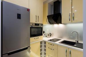 La cuisine est équipée de placards blancs et d'un réfrigérateur en acier inoxydable. dans l'établissement Apartament Marina View, à Giżycko