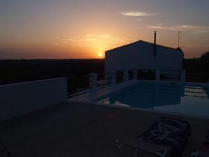 a sunset over a house with a swimming pool at Le Ville in Ferreries