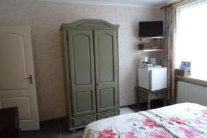a bedroom with a green cabinet and a refrigerator at Wondergem in Oostkapelle