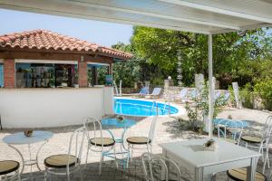 un patio con mesas y sillas junto a una piscina en Vivian Apartments, en Vlachata