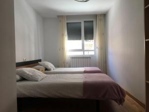 1 dormitorio con 2 camas y ventana en Alojamiento moderno y céntrico, en Soria