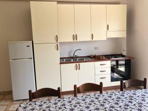 ガリポリにあるSpiaggia Baia Verde Gallipolitravelの白いキャビネット、シンク、冷蔵庫付きのキッチンが備わります。