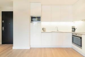 eine weiße Küche mit weißen Schränken und Holzböden in der Unterkunft Luxury Apartments - Okrzei Residence by Grand Apartments in Sopot