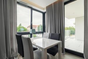a dining room with a white table and chairs and large windows at Luxury Apartments - Okrzei Residence by Grand Apartments in Sopot