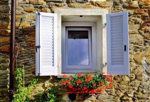 ein Fenster an einer Steinmauer mit Blumen in einer Fensterbox in der Unterkunft Pietrasanta in Pietrasanta