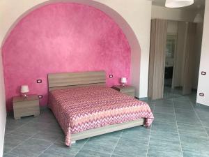 Dormitorio rosa con cama y pared de color rosa en Affittacamere Villa Zelinda en Sirolo